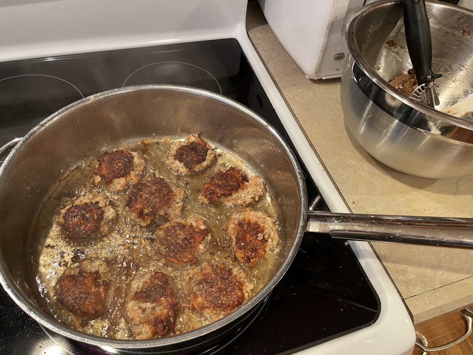 Frying ten chicken meat blobs for the Chicken Bun Cha recipe. I use a disher to dollop out a ball, flatten it, then cook few minutes on each side. The crispy exterior is pleasing.