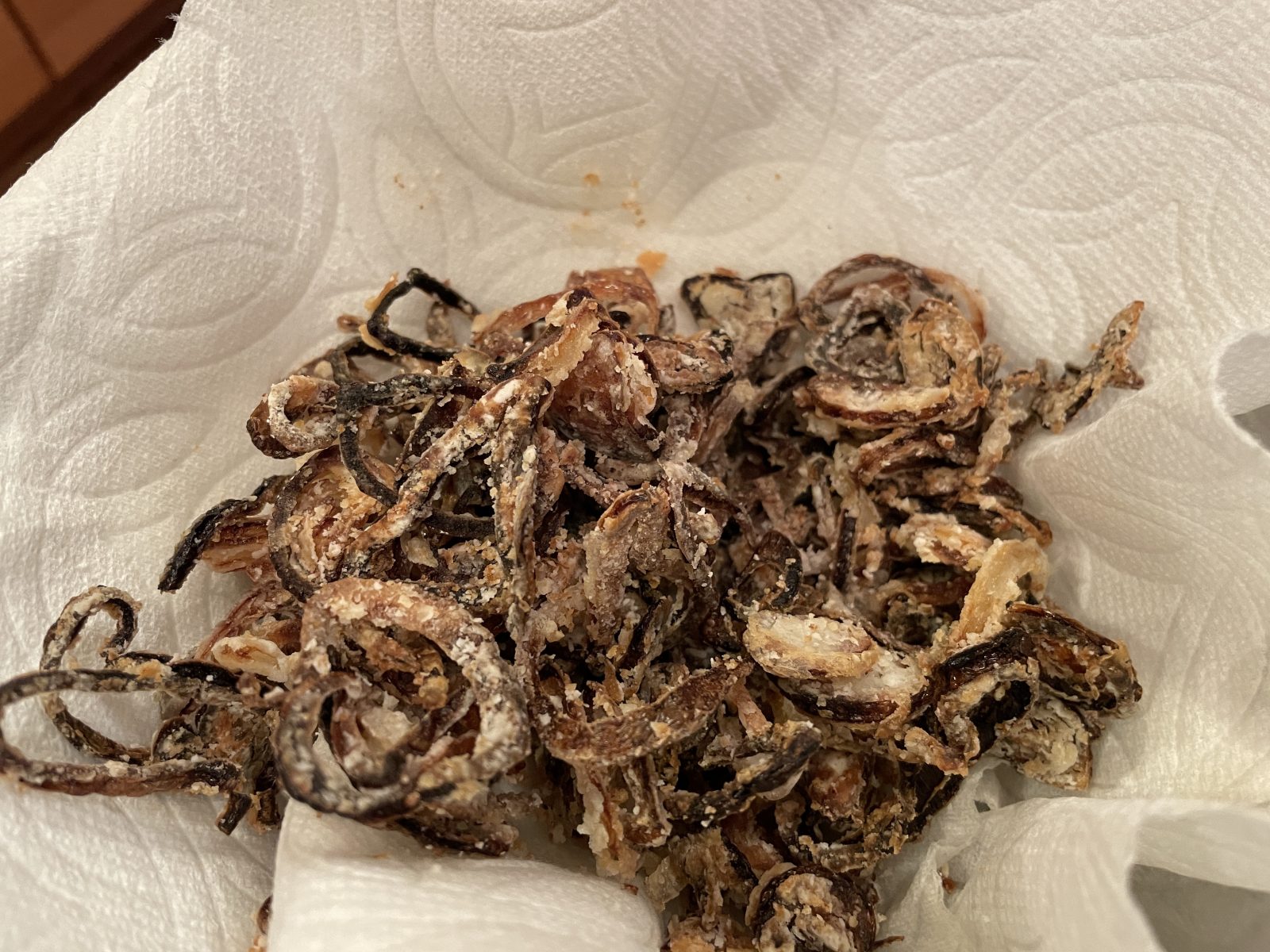 Fried shallots. After peeling then slicing the shallots, the individual rings are run through corn starch or flour to remove moisture. Fry for about 4-5 minutes at 325F until brown.